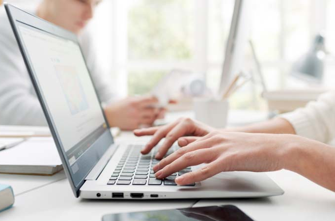 Person using laptop at desk with mobile